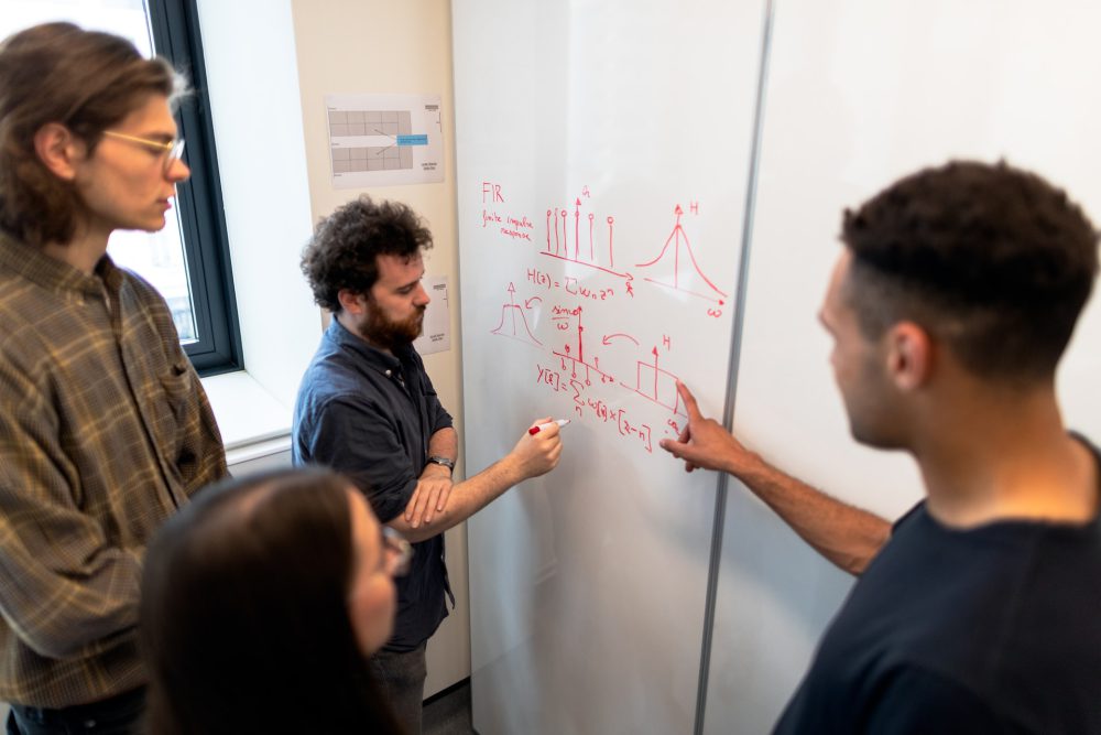 mensen staan rondom white board